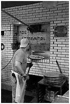 Man loading pizza into oven, Lombardi pizzeria. NYC, New York, USA (black and white)
