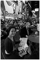 Woman with cupcakes sitting on Times Squares at night. NYC, New York, USA (black and white)