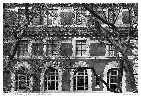 Trees and main building facade, Ellis Island, Statue of Liberty National Monument. NYC, New York, USA (black and white)