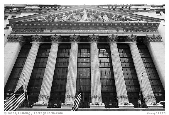 Looking up New York Stock Exchange with flags at half-mast. NYC, New York, USA