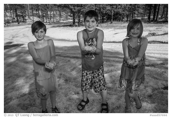 Children in summer dress holding large hailstones, Black Hills National Forest. Black Hills, South Dakota, USA (black and white)