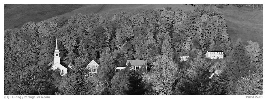 White-steppled church and houses amongst trees in fall foliage. Vermont, New England, USA (black and white)