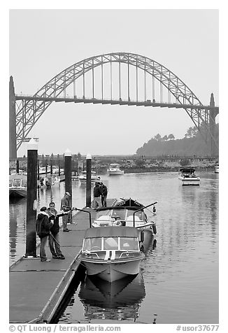 Couple holding small boat at boat lauch ramp. Newport, Oregon, USA (black and white)