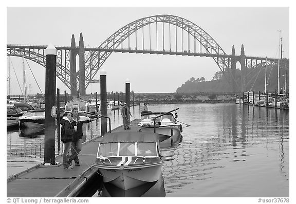 Couple holds  small boat on pier, Newport Marina. Newport, Oregon, USA (black and white)