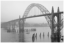 Small boat exiting harbor under Yaquina Bay Bridge. Newport, Oregon, USA ( black and white)