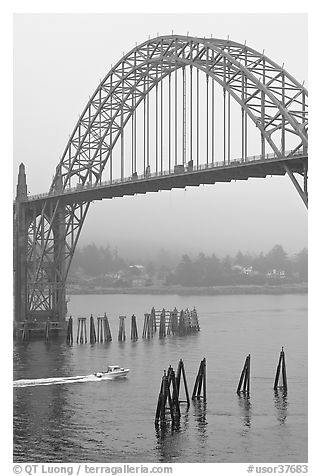 Small boat heading towards ocean under Yaquina Bay Bridge. Newport, Oregon, USA (black and white)