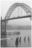 Small boat heading towards ocean under Yaquina Bay Bridge. Newport, Oregon, USA ( black and white)