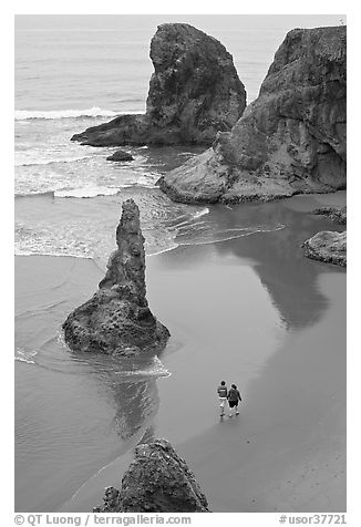 Women walking on beach among rock needles. Bandon, Oregon, USA