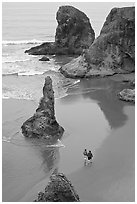 Women walking on beach among rock needles. Bandon, Oregon, USA (black and white)