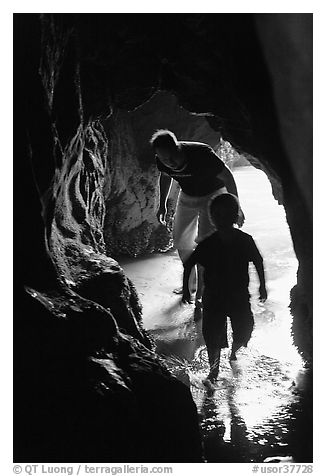 Boy and man exploring sea cave. Bandon, Oregon, USA (black and white)