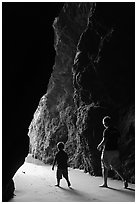 Father and son walking towards the light in sea cave. Bandon, Oregon, USA (black and white)