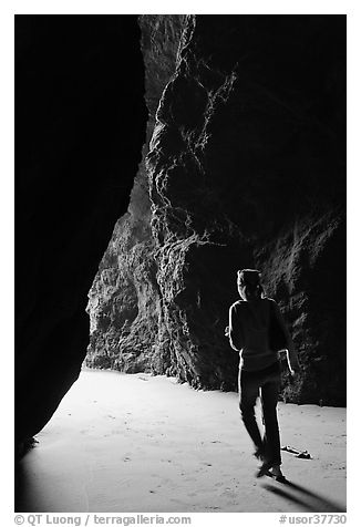 Woman walking out of sea cave. Bandon, Oregon, USA