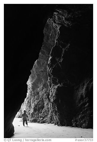 Infant walking into sea cave. Bandon, Oregon, USA (black and white)