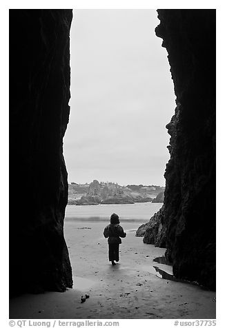 Infant standing at sea cave opening. Bandon, Oregon, USA