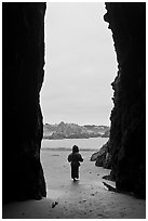 Infant standing at sea cave opening. Bandon, Oregon, USA ( black and white)