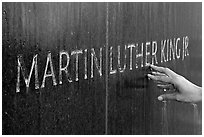 Hand touching the letters Martin Luther King on the Civil Rights Memorial wall. Montgomery, Alabama, USA ( black and white)