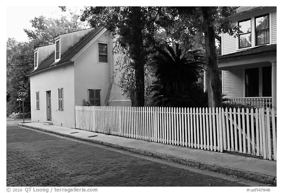 White picket fence and houses on cobblestone street. St Augustine, Florida, USA (black and white)