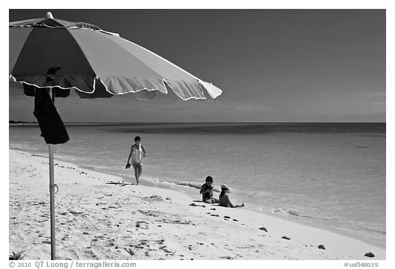 Beach with unbrella, children playing and woman strolling,. The Keys, Florida, USA (black and white)