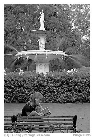 Woman sitting on bench with book in front of Forsyth Park Fountain. Savannah, Georgia, USA (black and white)