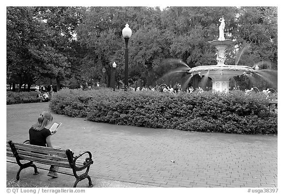 Forsyth Park Fountain with woman sitting on bench with book. Savannah, Georgia, USA