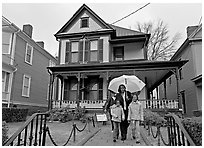 African American family with umbrella in front of Birth Home of Martin Luther King Jr. Atlanta, Georgia, USA (black and white)