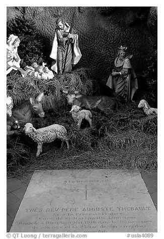 Tombstone of a French priest, and figures inside a replica of the Lourdes grotto, church Saint-Martin-de-Tours, Saint Martinville. Louisiana, USA (black and white)