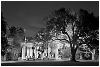 Antebellum mansion set in garden with  backlit oak tree at night. Natchez, Mississippi, USA (black and white)