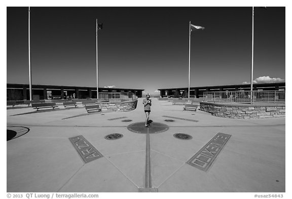 Woman straddling the territory of four states. Four Corners Monument, Arizona, USA (black and white)