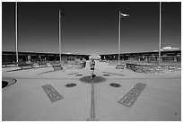 Woman straddling the territory of four states. Four Corners Monument, Arizona, USA (black and white)