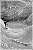 Hiker balances himself in the Wave. Vermilion Cliffs National Monument, Arizona, USA ( black and white)