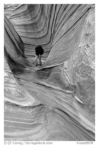 Hiker with backpack on a side formation of the Wave. Coyote Buttes, Vermilion cliffs National Monument, Arizona, USA (black and white)