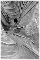 Hiker with backpack on a side formation of the Wave. Coyote Buttes, Vermilion cliffs National Monument, Arizona, USA (black and white)