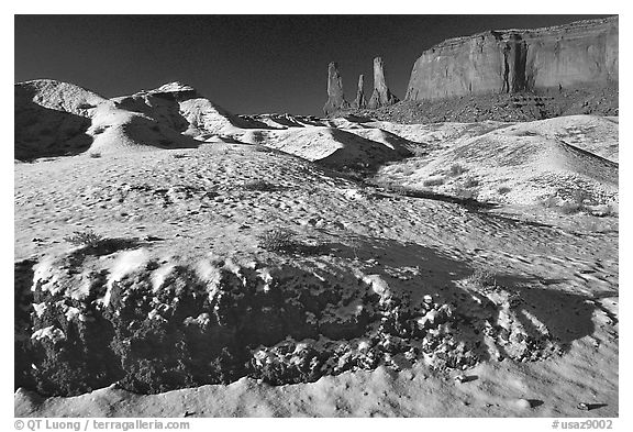 Snow on the floor, with Three Sisters in the background. Monument Valley Tribal Park, Navajo Nation, Arizona and Utah, USA (black and white)