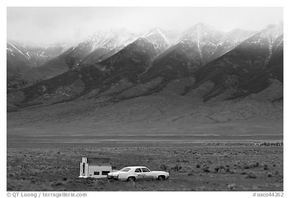 Car and pickup cover below snowy peaks. Colorado, USA