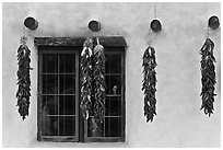 Yellow wall with ristras and blue window. Taos, New Mexico, USA (black and white)