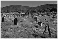 Headstones in grassy area, cemetery, Picuris Pueblo. New Mexico, USA (black and white)