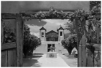 Church framed by doors with roses, Sanctuario de Chimayo. New Mexico, USA (black and white)