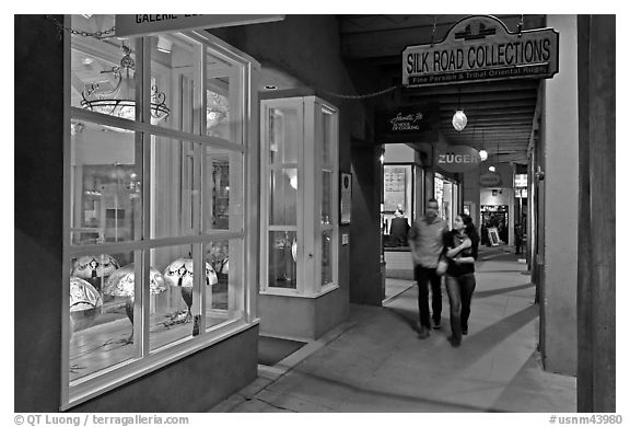 Couple walking by night in front of gallery. Santa Fe, New Mexico, USA