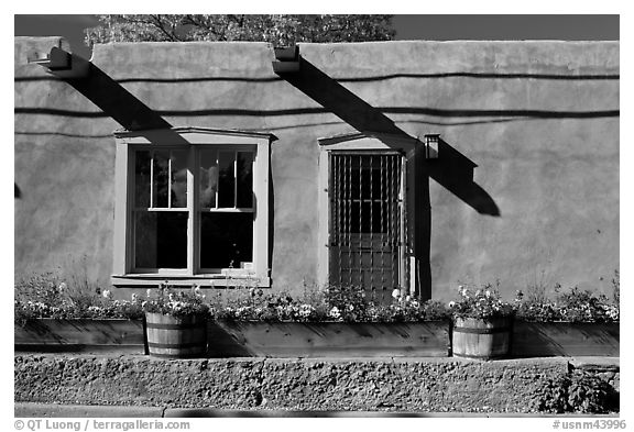 Adobe facade with flowers, windows, and vigas shadows. Santa Fe, New Mexico, USA