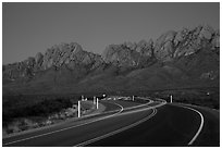 Road with light trails and Organ Mountains at dusk. Organ Mountains Desert Peaks National Monument, New Mexico, USA ( black and white)