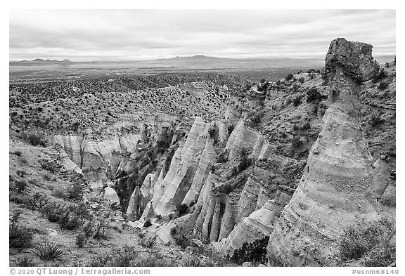 Tent rock with caprock overlooking mesa with distant Sangre de Cristo and Jemez Mountains. Kasha-Katuwe Tent Rocks National Monument, New Mexico, USA (black and white)