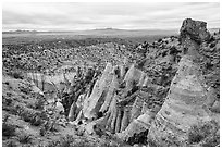 Tent rock with caprock overlooking mesa with distant Sangre de Cristo and Jemez Mountains. Kasha-Katuwe Tent Rocks National Monument, New Mexico, USA ( black and white)