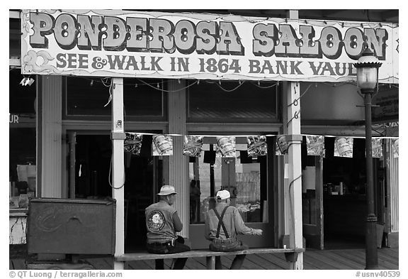 Men sitting on bench below Ponderosa Saloon sign. Virginia City, Nevada, USA (black and white)