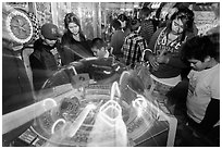 Family plays arcade game with spining lights. Reno, Nevada, USA ( black and white)