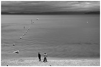 Men standing on beach under dark sky, South Lake Tahoe, California. USA (black and white)