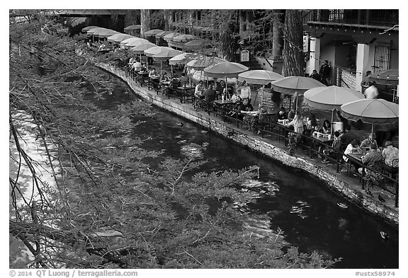 Tables under colorful umbrellas next to canal. San Antonio, Texas, USA (black and white)