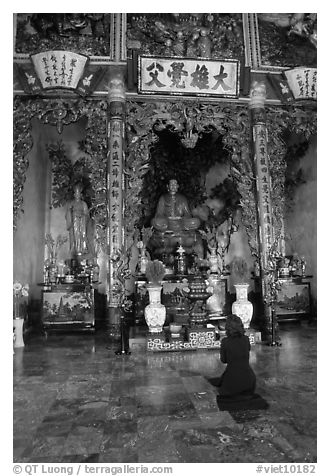 Woman praying at the altar. Ho Chi Minh City, Vietnam (black and white)