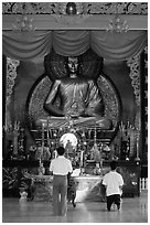 Men worshipping in front of a large Buddha state, Xa Loi pagoda, district 3. Ho Chi Minh City, Vietnam ( black and white)