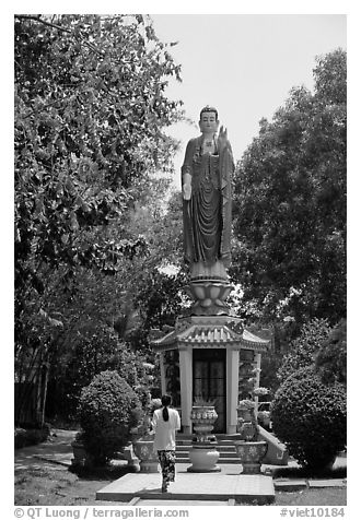 Woman praying under a large buddhist statue. Ho Chi Minh City, Vietnam