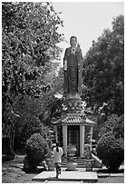 Woman praying under a large buddhist statue. Ho Chi Minh City, Vietnam ( black and white)